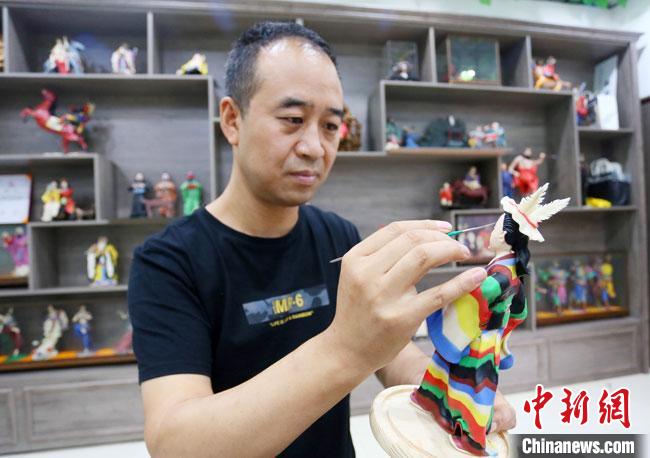 圖為安秋平正在創(chuàng)作代表隴南文縣民俗的《白馬人》作品?！「哒?攝