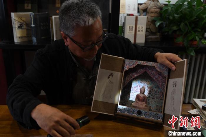 圖為讀者出版集團(tuán)讀者晉林工作室獨(dú)立出品人徐晉林，展示互動(dòng)性強(qiáng)的敦煌題材手工書(shū)。(資料圖) 楊艷敏 攝