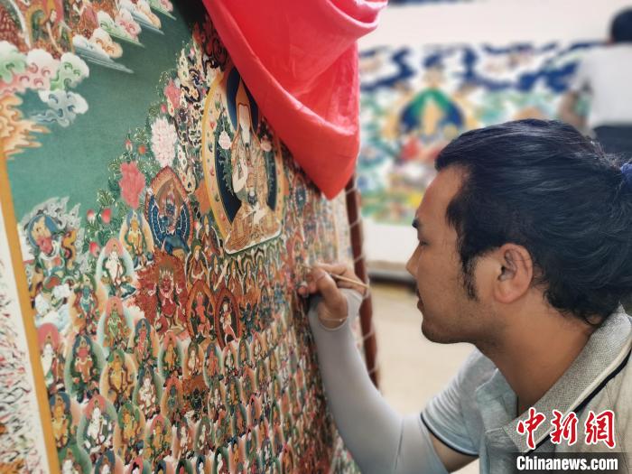 圖為更登才讓的徒弟繪畫唐卡?！?zhí)砀?攝