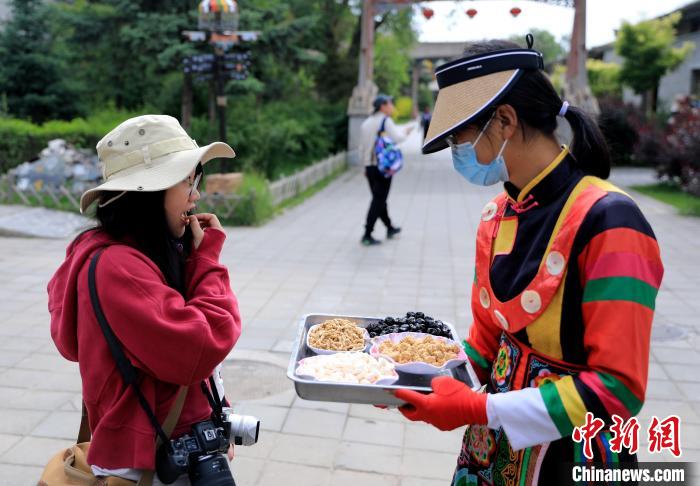 圖為身穿土族服飾的女性介紹當(dāng)?shù)靥厣〕??！⊙Φ?攝