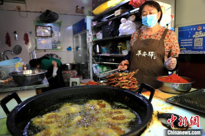 圖為平安驛·河湟民俗文化體驗(yàn)地內(nèi)的商戶炸干板魚?！⊙Φ?攝